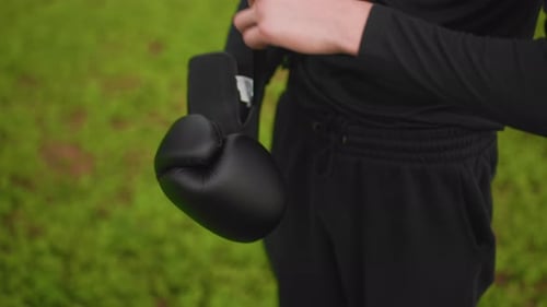 Man Putting On Black Boxing Gloves Outdoors