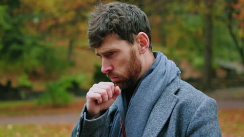 Sick Man Coughing and Blowing Nose in Park