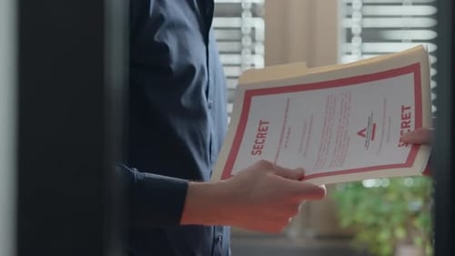 Two men exchange secret document files in yellow folder inside corporate office. Mysterious shady su