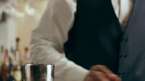 Bartender pouring classic daiquiri cocktail using strainer in modern bar