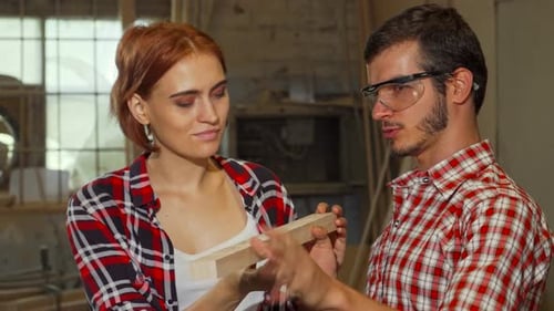 Skilled Male Carpenter Guiding His Female Assistant in a Vibrant Workshop