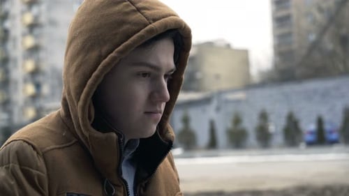 Nachdenklicher Teenager steht allein inmitten von Stadtgebäuden, in Gedanken versunken