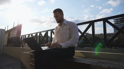 Successful Entrepreneur Works on Notebook Sitting on Bench at City