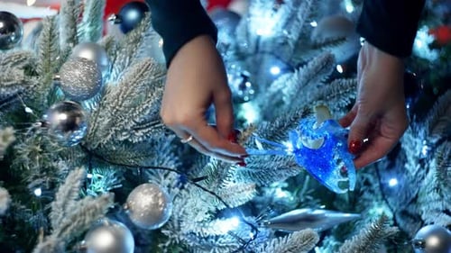 Woman Decorating Christmas Tree with Blue Ornaments