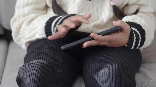 Young Girl Uses Mobile Phone While Seated