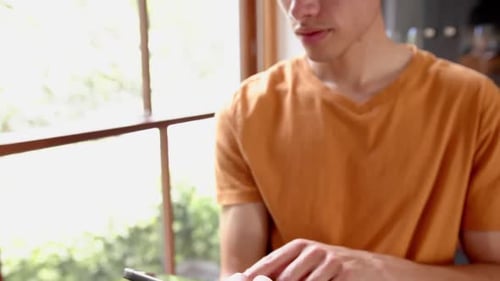 Young Adult Using Tablet Indoors by Window
