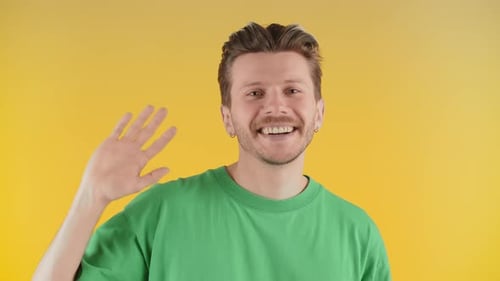 Smiling Man Waving on Yellow Background