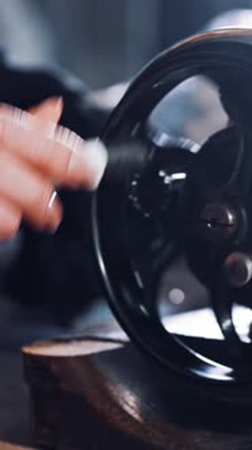 Close-up of woman's hand spinning the metal wheel of an old sewing machine.