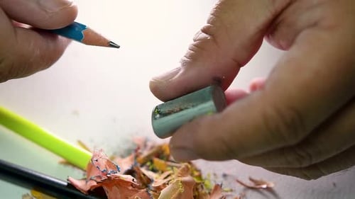 Footage of hands slowly sharpening a pencil and some coloured pencils with a Wedge Pencil Sharpener.