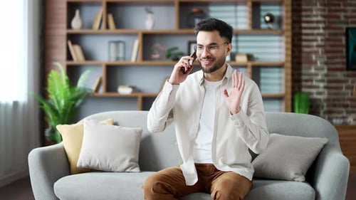 Man Sitting on Couch Talking on Phone