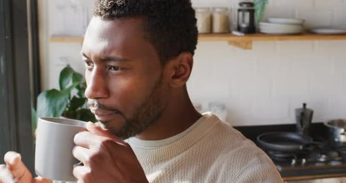 Young Adult Drinking from Mug in Kitchen