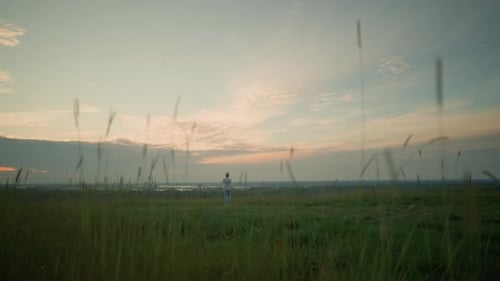 Contemplative Moment Man Gazing at Grass in Tranquil Field at Sunset