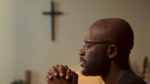 Man Praying in Chapel with Cross