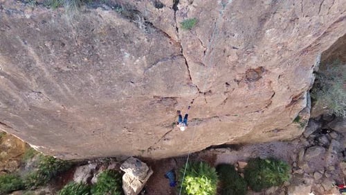 Aerial view of Sportswoman rock climbing in slow motion at a wall rock