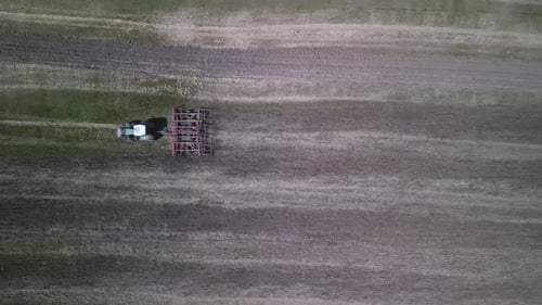 Traktor arbeitet auf dem Feld bei der Bodenbearbeitung mit Grubber