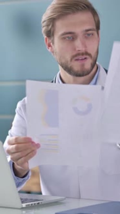 Médecin avec ordinateur portable lisant des documents au bureau, Vidéo verticale
