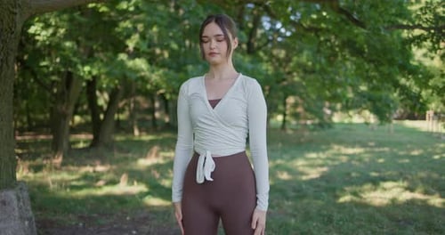 Young Beautiful Athletic Woman in Sportswear Doing Stretching and Warming Up in the Park Near a Tree