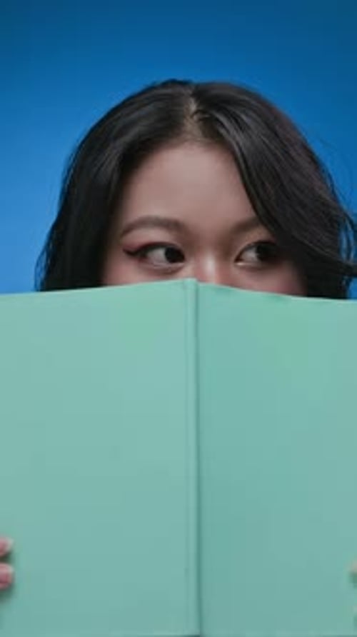 Smiling Young Woman with Book on Blue Background