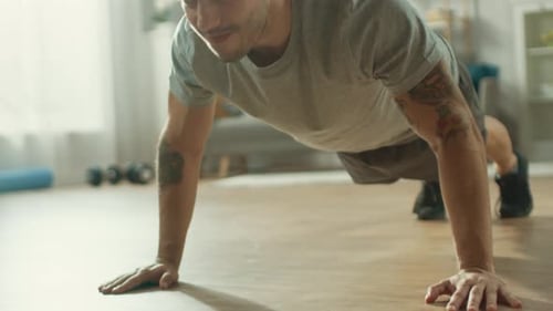 Close Up of a Strong Athletic Fit Man in T-shirt and Shorts is Doing Push Up Exercises at Home in H