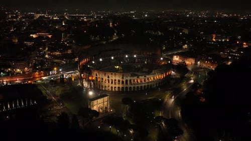 Aerial fly drone view of Colosseum or Coliseum at night, Rome, Italy, Europe. Ancient Roman ruin is