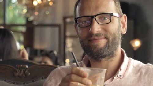 Portrait of Happy, Young Man Drinking Cocktail in Cafe 30s