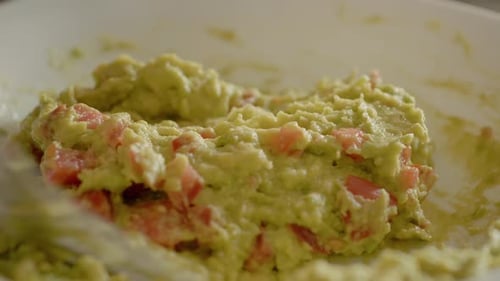 Preparing Delicious Guacamole with Tomato in a Bowl