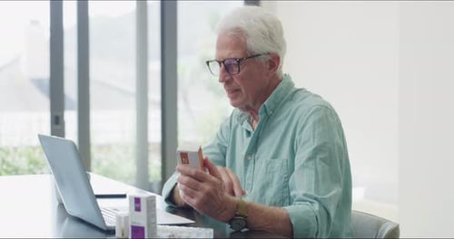 Senior Man Using Laptop with Medicine