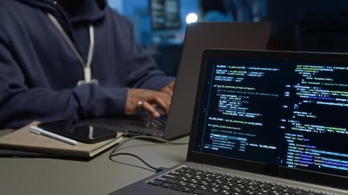 Hacker Typing Code on Laptop in Dark Office