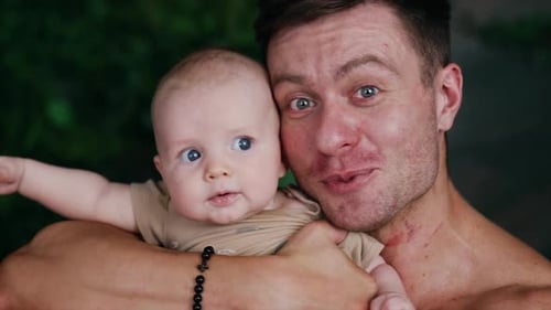 Handsome Caucasian man holding an infant child close to his face.