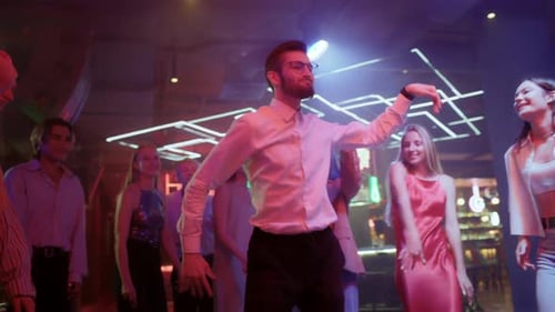 Gruppe junger Freunde tanzt zusammen im Neonlicht des Nachtclubs. Energetische verspielte Bewegungen in Di...