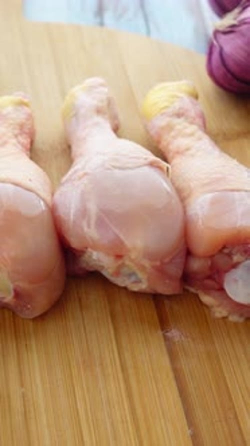 Uncooked Chicken Drumsticks on a Wooden Cutting Board