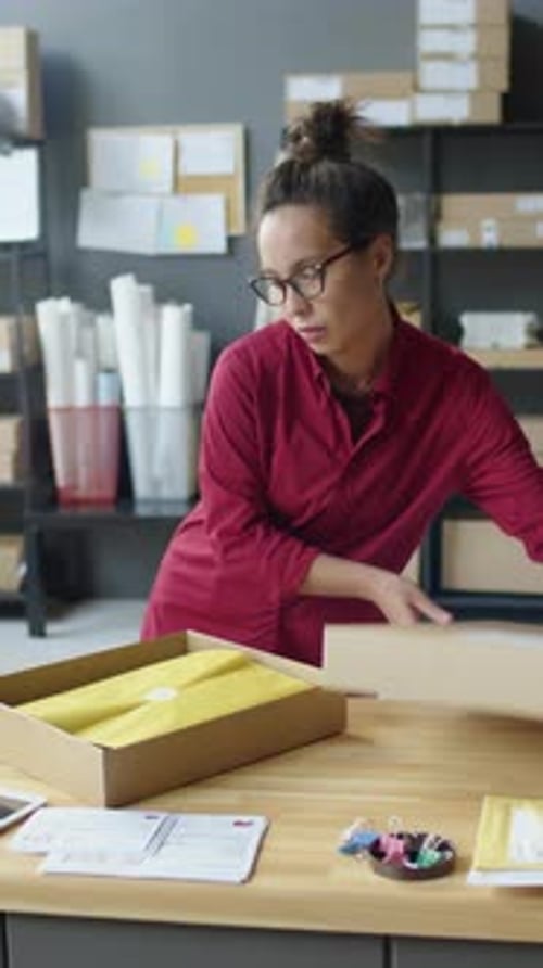 Weibliche Lieferdienstmitarbeiterin beim Verpacken von Paketen
