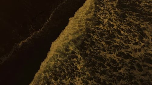 Drohnenaufnahme des Strandsandes mit den Wellen des Ozeans.