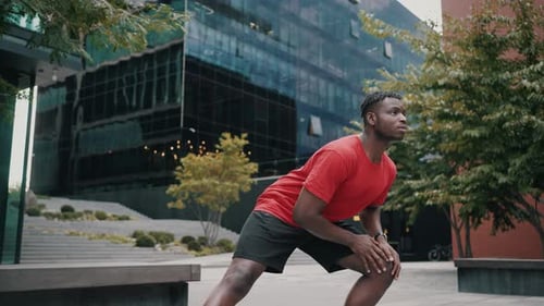 Sportive Athlete Stretching Muscles on Urban Street