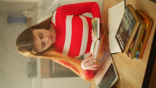 Girl Reading Book with Laptop on Desk