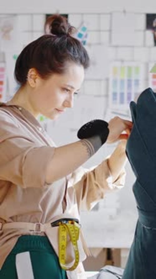 Junge Modedesignerin fertigt im Workshop ein Kleidungsmuster an und arbeitet mit Stoff und Modell
