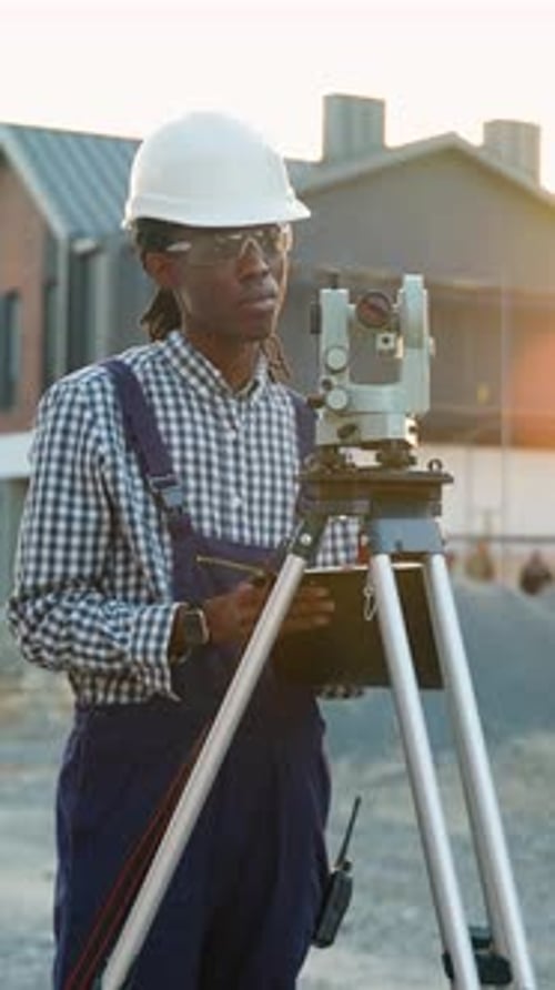 African American Surveyor Using Theodolite in a Modern Cottage Town