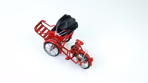 Red Tricycle Model Spinning on White Surface