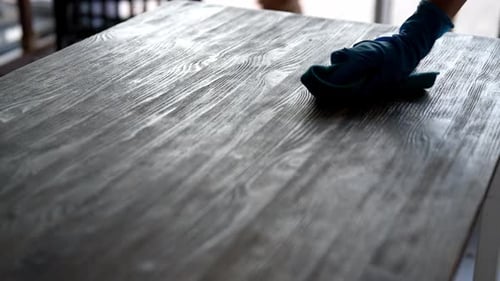 Gloved Hand Wipes Wooden Table Close Up