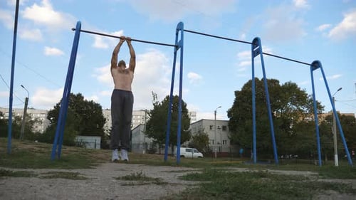 Muscular Athlete Doing Pull Ups at Sports Ground Young Sportsman Exercising on Horizontal Bar at