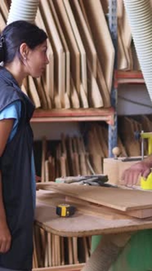 Woman and Man Inspecting Wood at Carpentry Workplace
