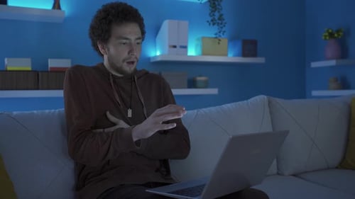 Man Reacts with Shock to Laptop Screen at Night