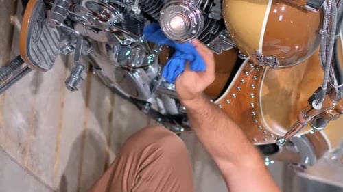 A Young Man in a Garage Near a Motorcycle He Rubs the Chrome Engine Until It Shines Vertical Video