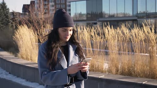 Young Woman Using Smart Phone in Sunny Urban Winter Park Adult