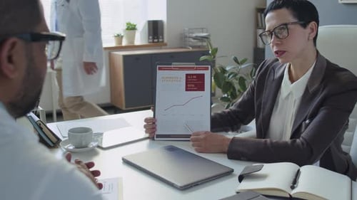 Female Manager Presenting Statistical Data to Chief Physician at Office Meeting