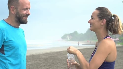 Couple Resting, Drinking Water After Jogging on Beach Adult