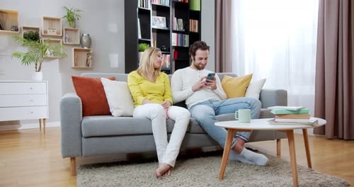Couple Relaxing on Couch Using Phone in Living Room