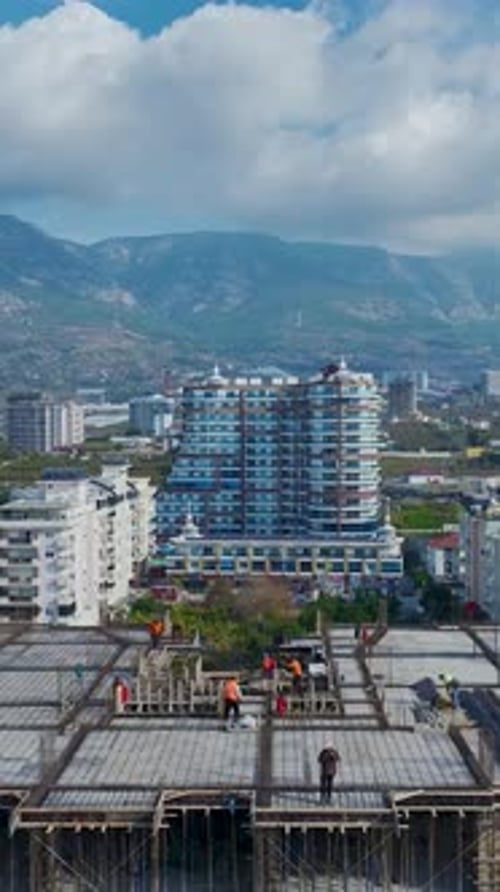 Vista aérea vertical de vídeo del sitio de construcción con trabajadores