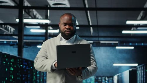 Man Uses Laptop in a Modern Data Center