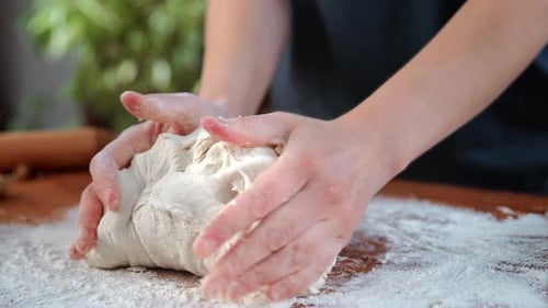 Hausfrau kocht hausgemachten Teig für Brot oder Kuchen, Nahaufnahme einer Frau in den Händen auf dem Küchentisch